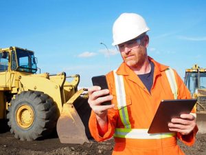 Construction manager checking safety forms and reports on mobile